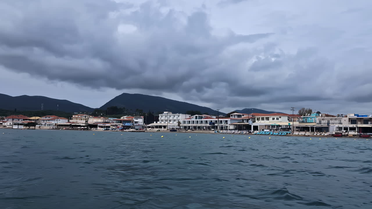 Coastal Village and Beach with Mountains Under Cloudy Sky