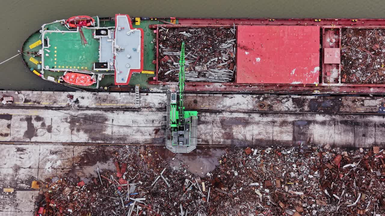 Una nave scarica il carico nel cantiere navale mentre una gru lavora nell'area del molo.