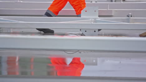 Zeitlupenaufnahme-Von-Bauarbeitern,-Die-In-Fluoreszierender-Kleidung-Auf-Einer-Nassen-Baustelle-Laufen