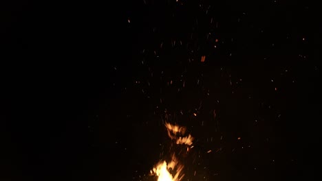 Sparks-and-flame-from-bonfire-on-black-sky-background,-slow-motion