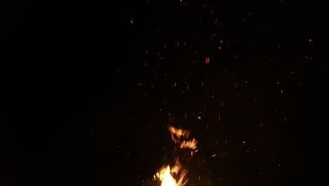 sparks and flame from bonfire on black sky background, slow motion