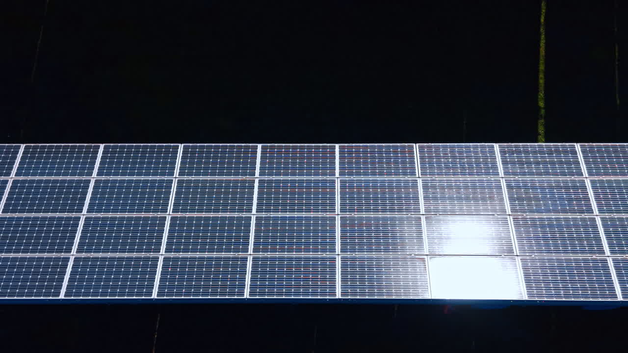 Dettaglio della superficie di un pannello solare con un brillante bagliore solare. Vista aerea che mostra la struttura a griglia delle celle solari e un forte riflesso del sole.