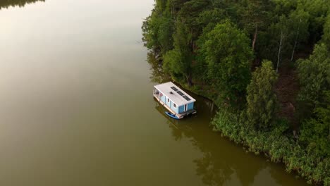 house boat floating on a lake next to a forest in brandenburg, germany