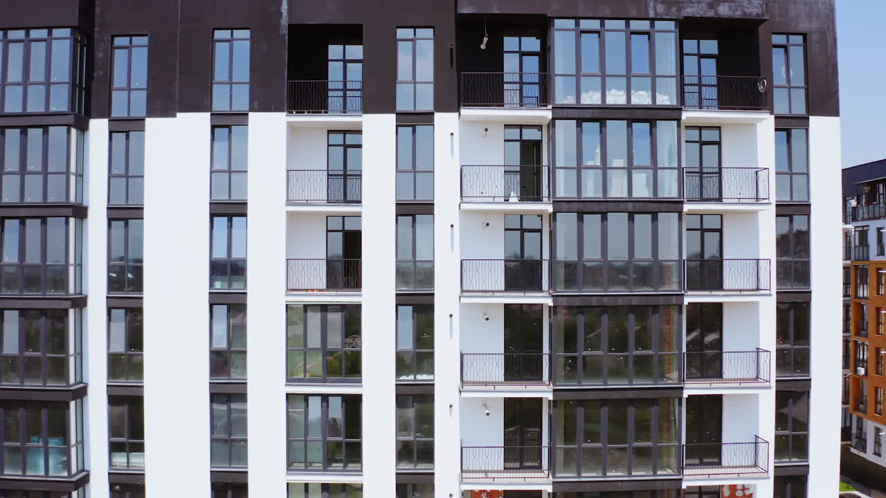 Black and white block of flats. Front view of a modern multi-storey building with glazed balconies in the city. Beautiful new housing apartments.