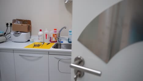 Pan-left-shot-of-open-door-revealing-dental-tools-and-equipment-in-room