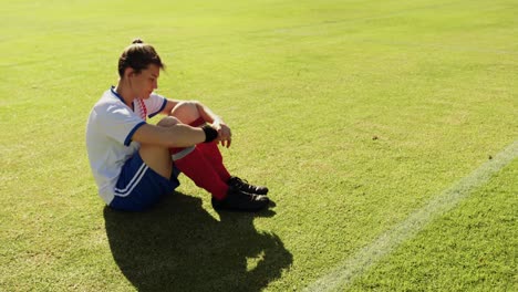 Female-soccer-player-sitting-on-soccer-field.-