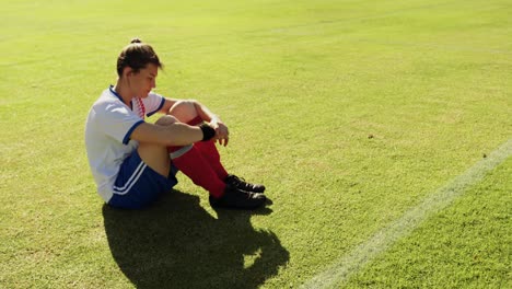 female soccer player sitting on soccer field.