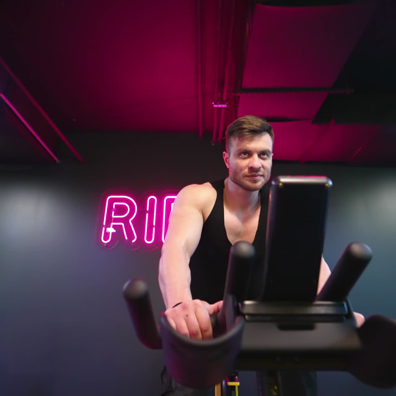 Speedy bicycle ride in fitness centre. Fitness man athlete training using exercise bike in gym