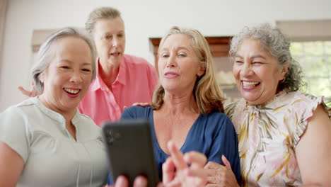 Eine-Gruppe-Hochrangiger,-Vielfältiger-Frauen-Lacht-Und-Schaut-Auf-Ein-Smartphone