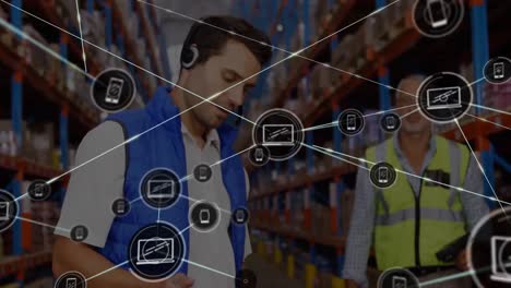 Animation-of-connected-phone-and-laptop-icons-over-caucasian-male-foremen-working-in-warehouse