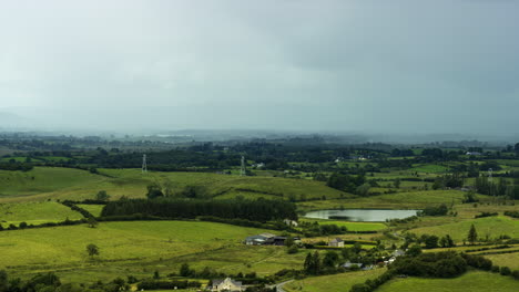 Lapso-De-Tiempo-Del-Paisaje-Agrícola-Rural-Con-Campos-De-Hierba,-Lago-Y-Colinas-Durante-Un-Día-Lluvioso-De-Tormenta-En-Irlanda