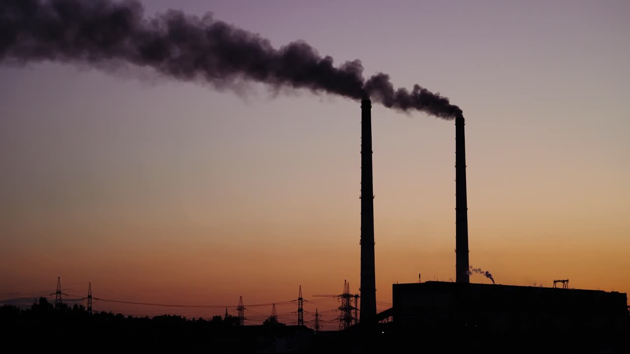 Dark smoke from pipes on the evening sky. Dirty emissions from pipes of industrial plant pollute the environment. Ecological problems.