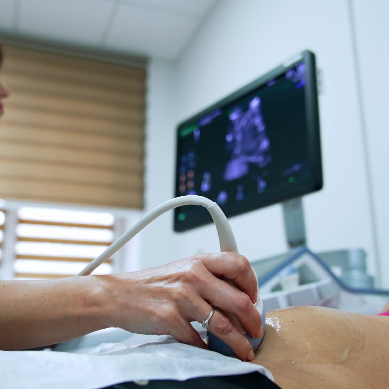 Dark-haired female doctor checks the pregnant woman at ultrasound machine. Medic mover the transducer by belly and looks at the monitor intently. Low angle view