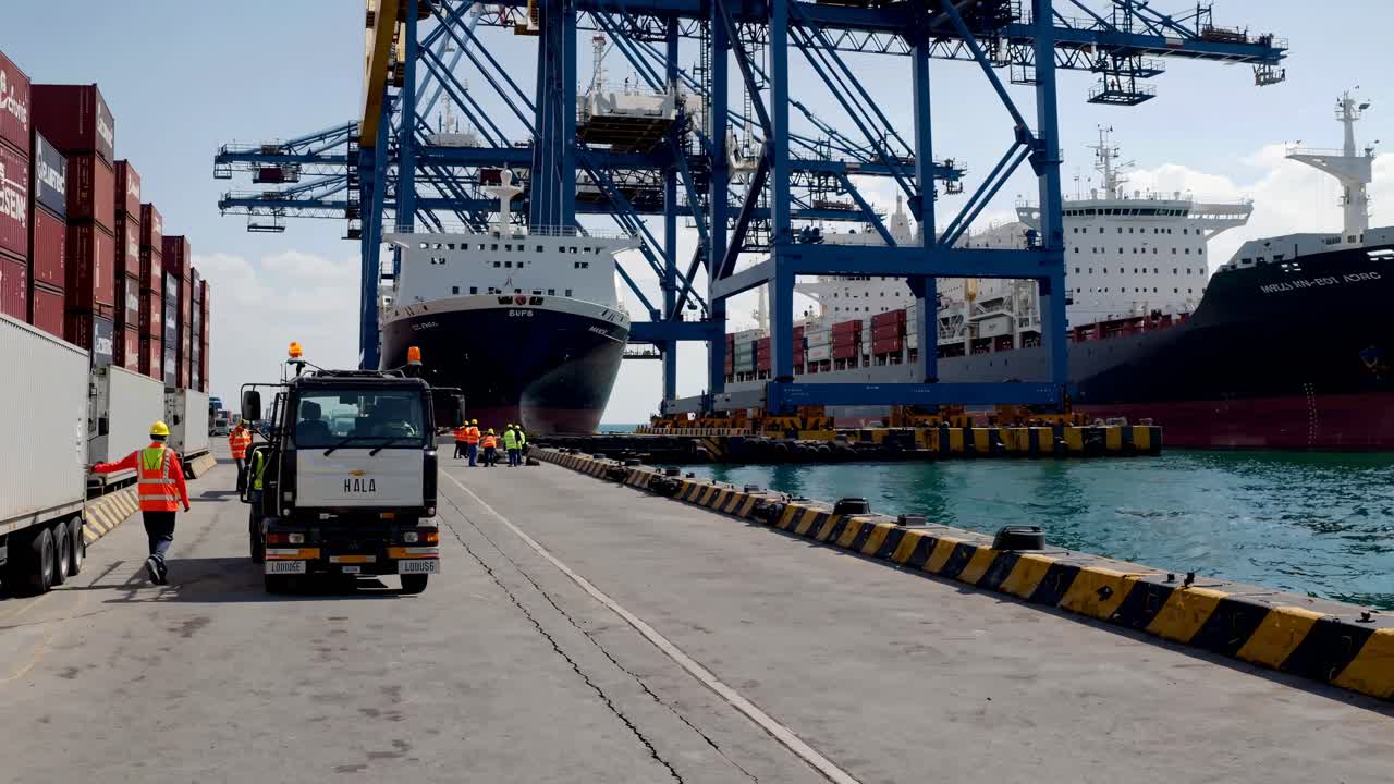 Wide-angle shot of a bustling port with cranes, ships, and workers in high-visibility vests