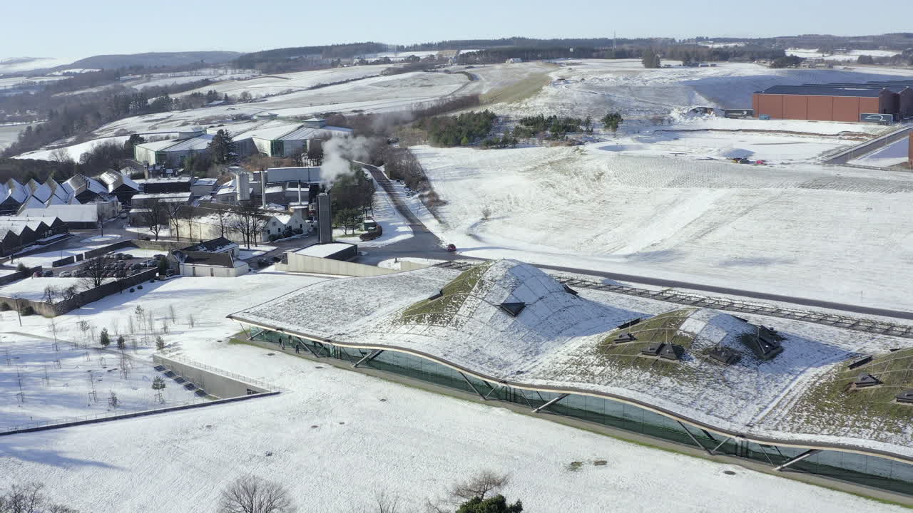 화창한 겨울날 눈으로 둘러싸인 맥캘란 위스키 양조장의 공중 전망, 모레이, 스코틀랜드 - 전진 샷 - 라이징 샷