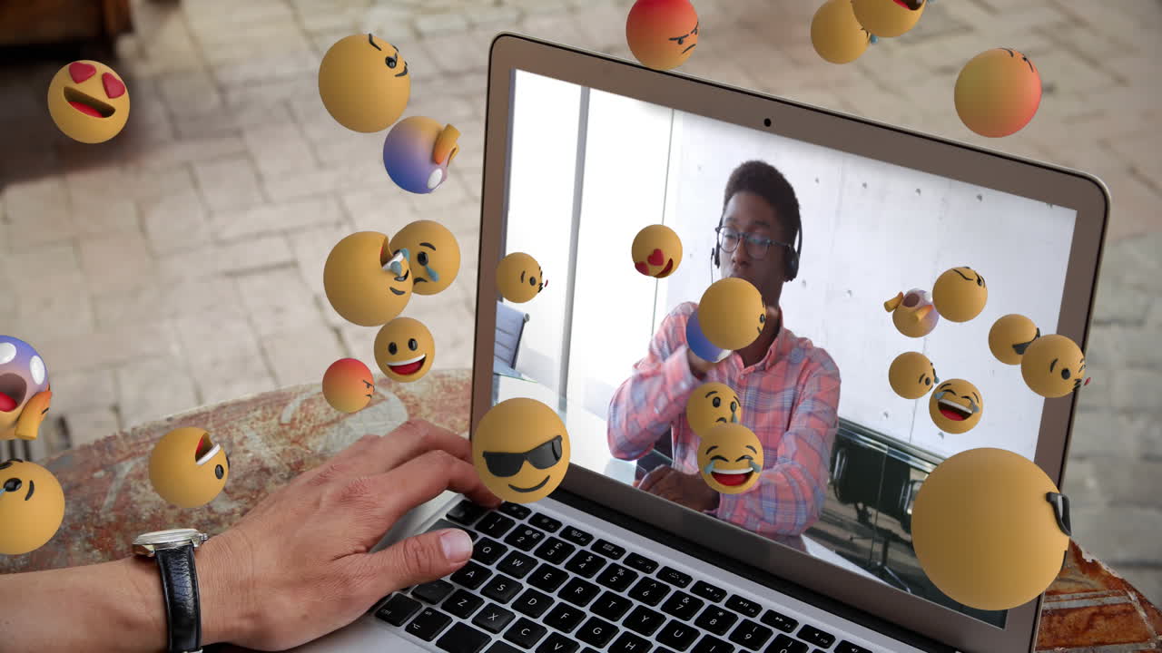 grupo de iconos emoji que fluyen sobre el hombre en la pantalla del portátil.