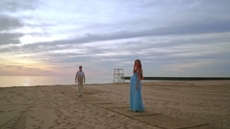 Man-walking-towards-his-pregnant-wife.-Romantic-photo-session-on-beach