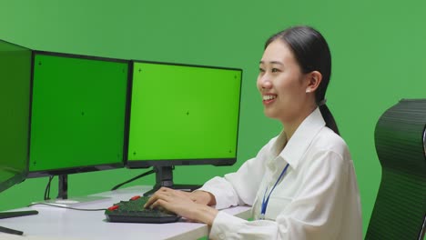 woman working at a computer in front of a green screen