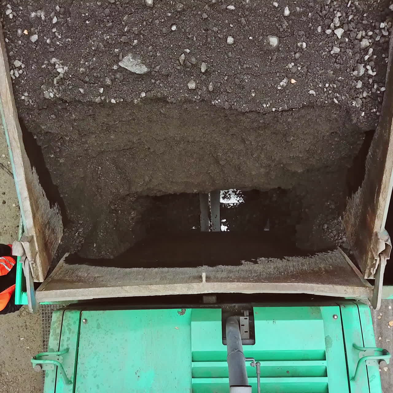 Top view of a truck with blacktopping outdoors. Aerial view of black bitumen pouring out from the machine into the road. Process of asphalting.