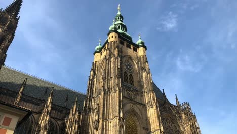 clock tower of st vitus cathedral in prague rises into blue sky, low angle