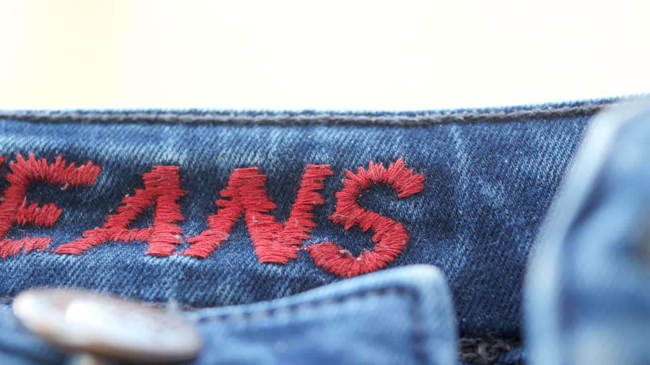 Close up of jeans with red embroidery