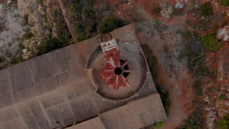 Rusty-roofed-quicklime-factory-ruins-in-Portugal,-top-down-aerial-view,-rotating-clockwise