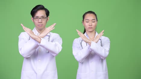 young asian couple doctors with stop gesture together