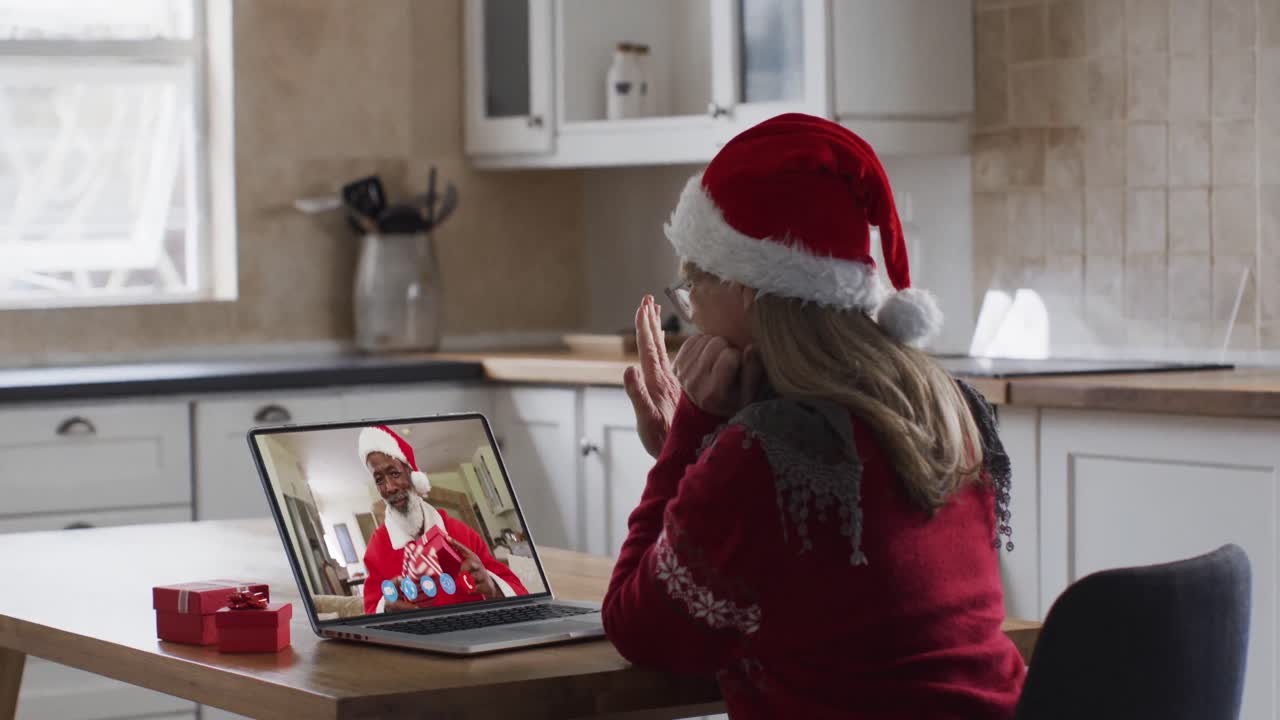 mujer caucásica con sombrero de papá noel en una videochat portátil durante la navidad en casa