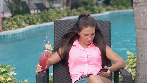 lady in denim shorts pink sleeveless blouse rests by pool