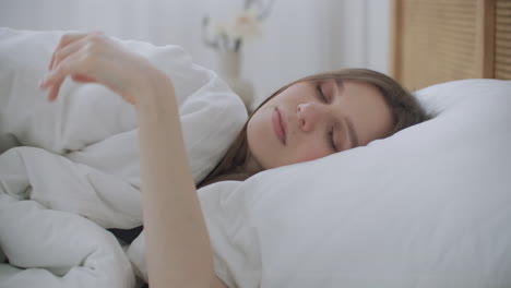 Sick-woman-sleeping-in-bed-under-blanket.-Woman-covering-her-ears-with-a-duvet.-Young-woman-hide-under-blanket-on-a-bed.