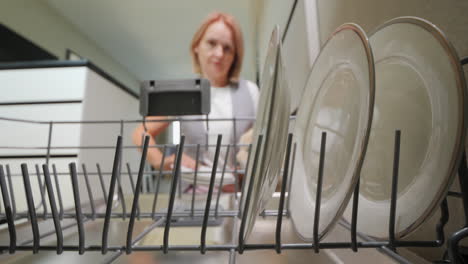 Cute-woman-takes-clean-plates-from-the-dishwasher.