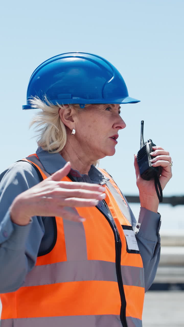 Donna professionista con cappello e giubbotto di sicurezza che usa un walkie-talkie.