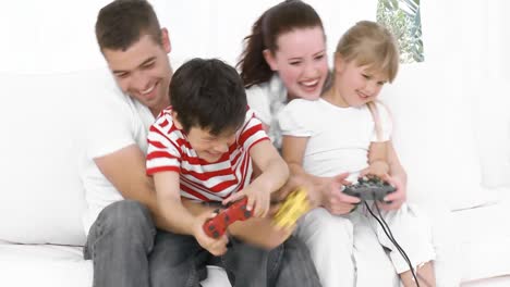 la familia en casa jugando videojuegos en el sofá