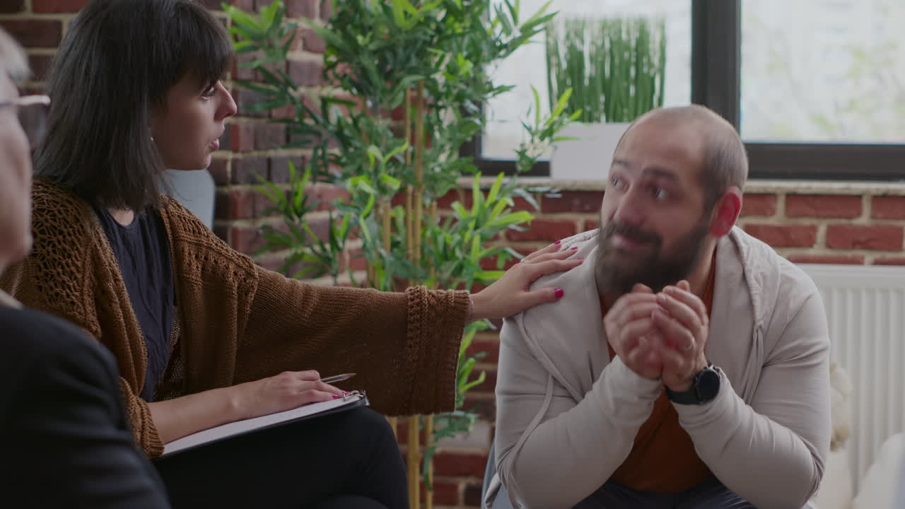 Close up of man trembling and shaking at aa group therapy session with people in circle