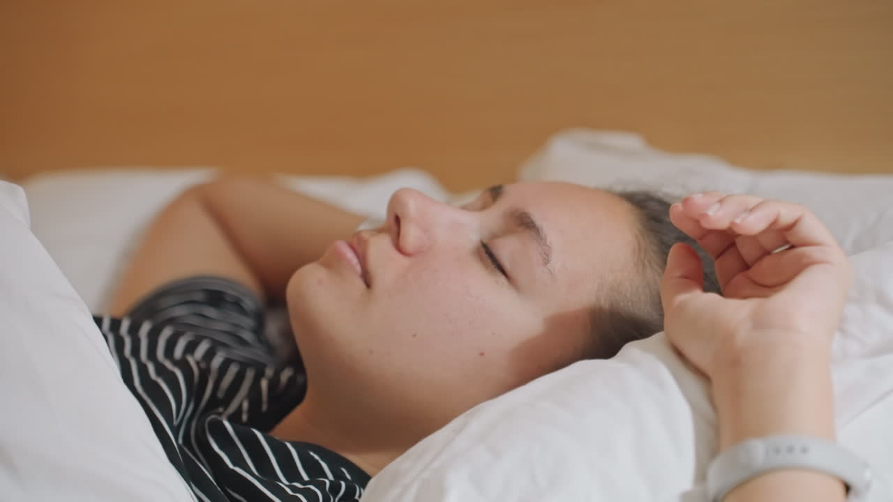 Kvinde slapper fredeligt af. Rolig kvinde vågner langsomt indenfor. Morgenro, mens kvinden blidt strækker sig vågen. Fredfyldt morgenstund med kvinde, der strækker sig i et blødt oplyst hotelværelse.
