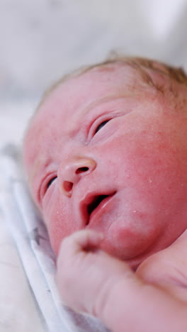 naked pink caucasian newborn lying on the back. lovely baby opening eyes and mouth. close up. vertical video