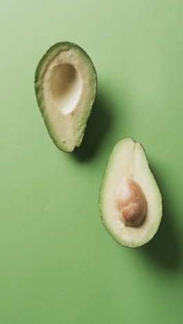 vertical video of sliced avocado with copy space over green background