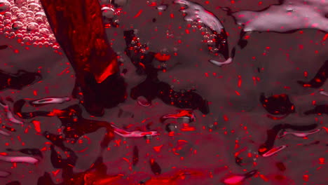 Closeup-red-liquid-filling-wineglass-super-slow-motion.-Wine-splashing-bubbling