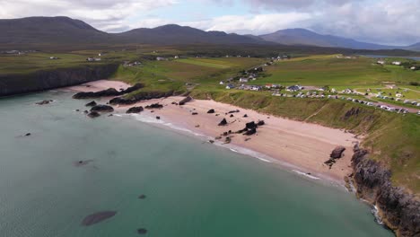 una tranquila playa de arena en escocia rodeada de acantilados y colinas verdes