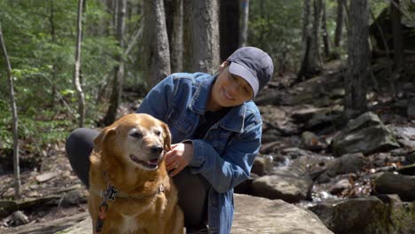 pretty young diverse woman petting her senior dog outdoors in nature