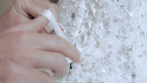 slow motion macro shot of a bride's wedding dress being tied in a bow at the back