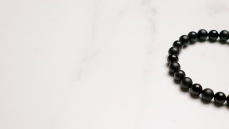 panning from the right to the left side of the frame showing a bracelet made out of tiny black beads