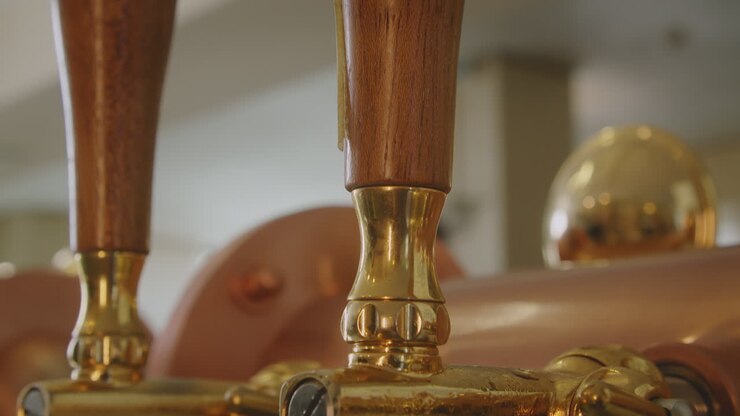 Close up tilt down on a vintage golden, brass and wood beer pump