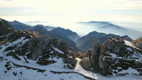 Hiker-explorer-walking-on-snowy-ridge-mountain-with-breathtaking-views-of-Alps-range-in-background,-Resegone-in-Italy