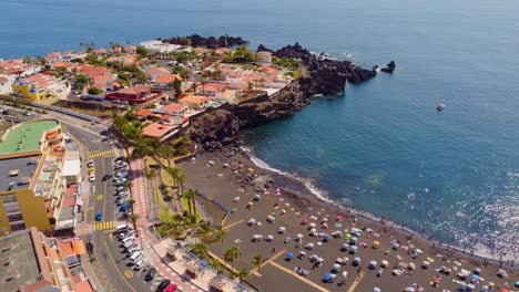 Vista-Aérea-De-La-Concurrida-Playa-De-La-Arena,-Tenerife,-Con-Arena-Volcánica-Negra