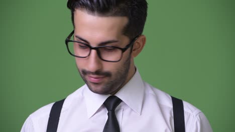 joven empresario persa barbudo y guapo contra un fondo verde