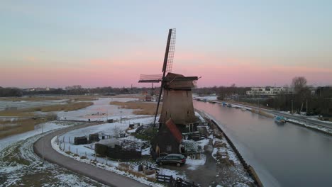 Molino-De-Viento-Holandés-Junto-Al-Río-Con-Nubes-Rosadas-En-El-Fondo-Al-Amanecer