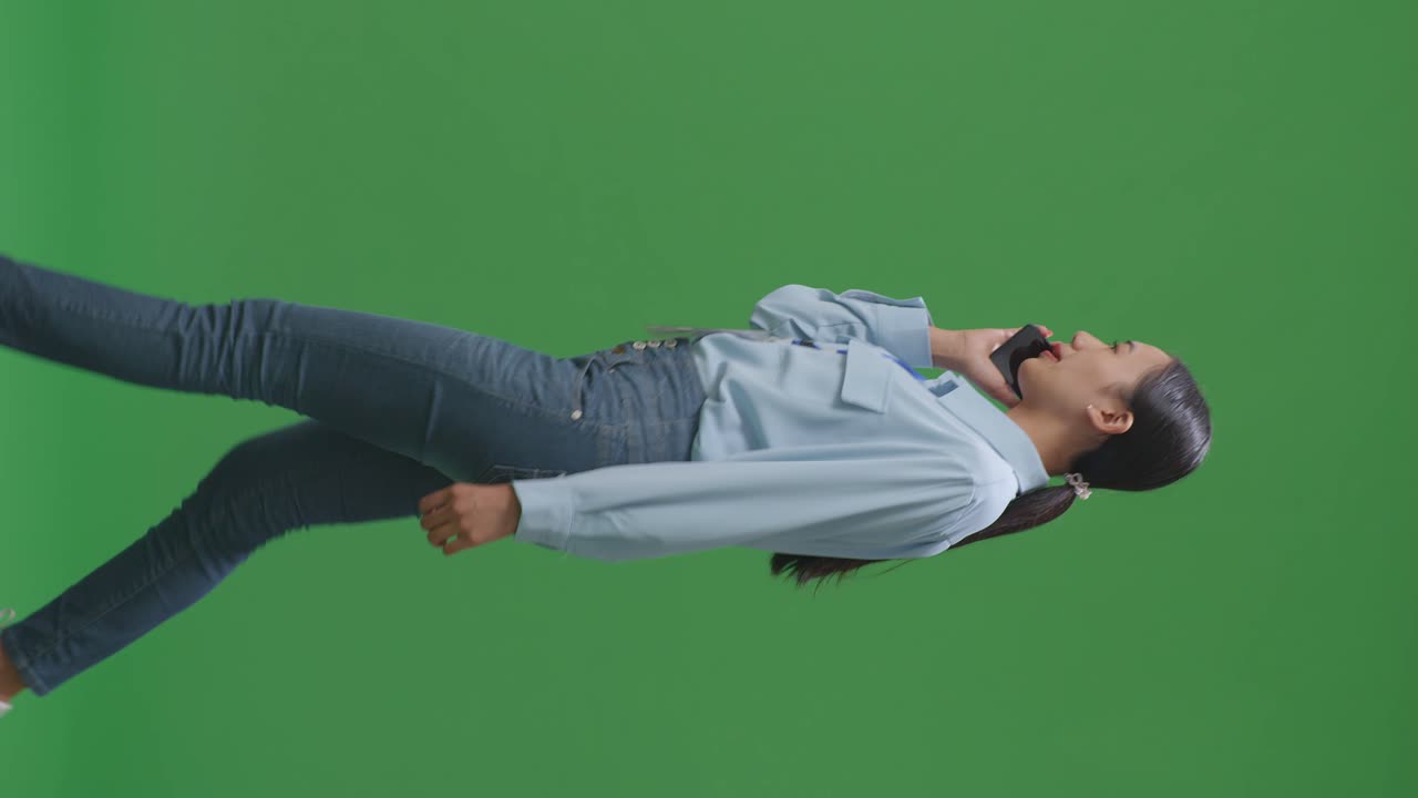 스튜디오에서 녹색 화면을 는 동안 휴대 전화로 이야기하는 아시아 사업가의 측면 시각