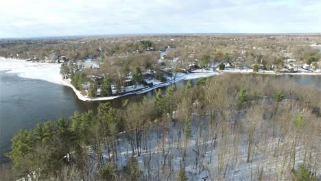 sliding drone shot of summer and winter houses surrounding a lake