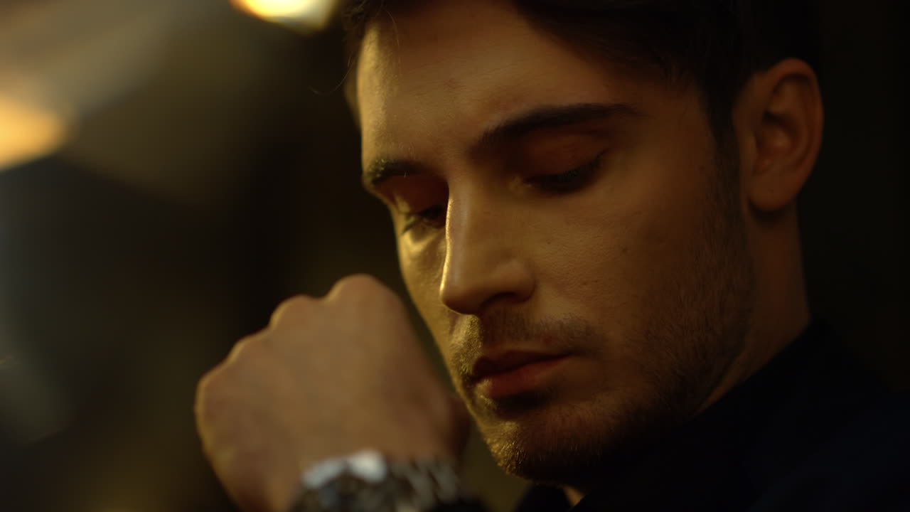 예쁜 남자의 얼굴은 내부에서 멀리 보입니다. 사려 깊은 남자는 실내에서  ⁇ 을 만지고 있습니다.